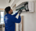 Professional AC technician repairing a split air conditioner in a modern Abu Dhabi home interior